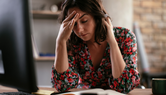 Person holding their head while working at a desk, headache evaluation in Racine, WI