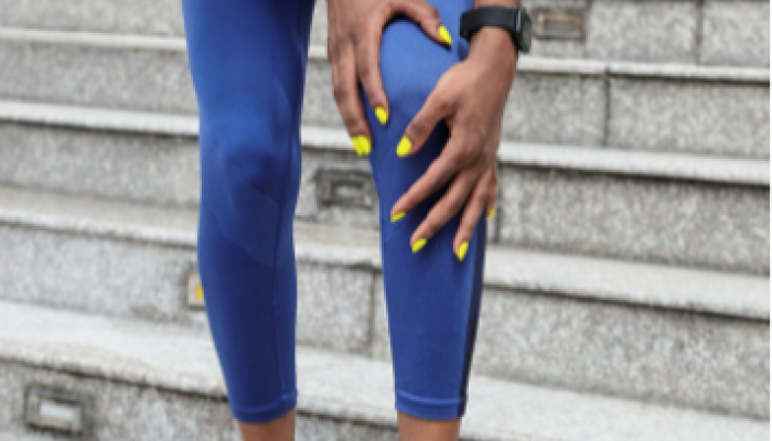 Runner holding the front of her knee, patellofemoral pain treatment in Racine, WI